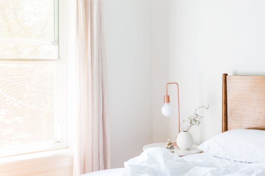 White bed room with soft peach curtains creating a serene bedroom